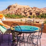 Young,Woman,Tourist,Sitting,On,Hotel,Terrace,In,Orange,Hat